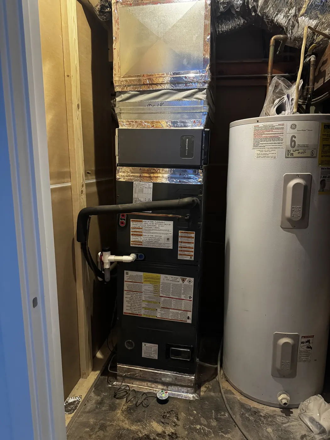 An air handler and an electric water heater installed side by side in a narrow closet