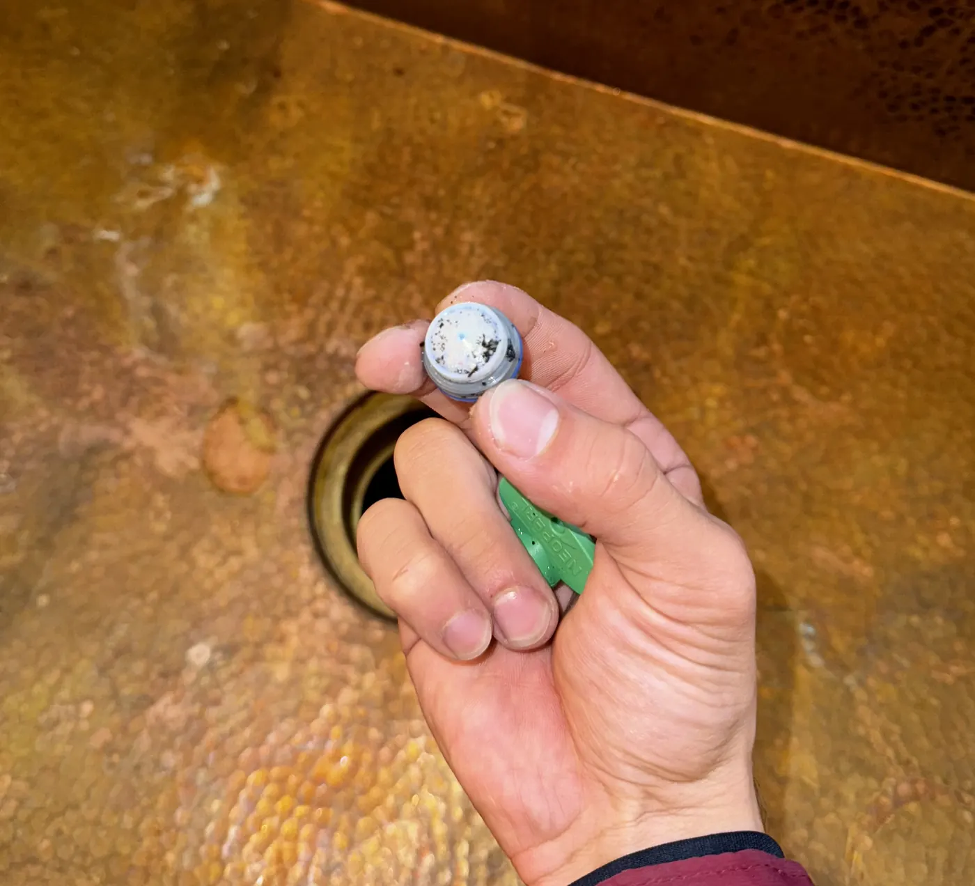 A hand holding a faucet aerator clogged with mineral scale
