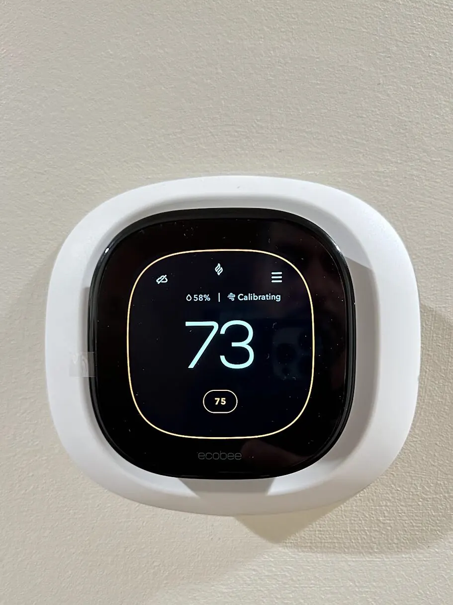 A new ecobee smart thermostat on a wall reading 73 degrees